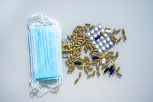 A Table With Several Surgical Masks. Assorted Pharmaceutical Medicine Pills, Tablets And Capsules Near The Masks. High Quality Photo