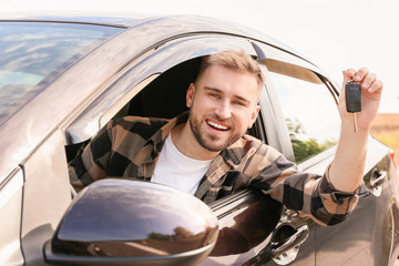 Poster - Happy young man with key sitting in his new car