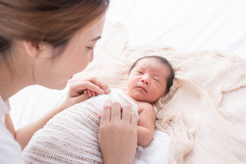 Wall Mural - woman and new born boy relax. mother breast feeding baby. family at home. happy mother and baby. young mother holding her newborn child. mom nursing baby. mother and baby child on a white bed.