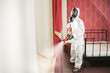 © Parilov - Disinfecting prevent COVID-19, specialist in hazmat suit with disinfect in hotel. Concept coronavirus pandemic clear