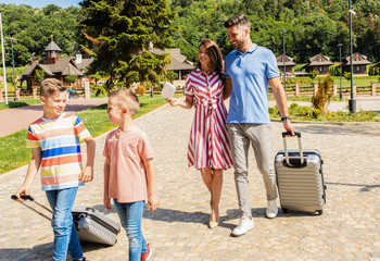 Wall Mural - smiling family of four going to the hotel to check in at the reception for vacation.