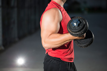 Bodybuilder trains with weights in the outdoor gym.