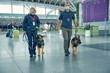 Security workers with detection dogs walking in airport terminal