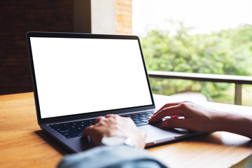 Mockup image of a woman using and typing on laptop computer keyboard with blank white desktop screen on wooden table