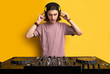 © Roman - dj man in white headphones behind dj console, makes song with dj controller. long haired caucasian guy in cool stylish wear posing on isolated background