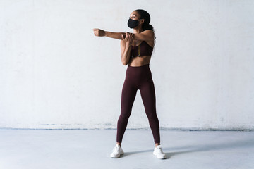 Photo of athletic african american woman in face mask doing exercise