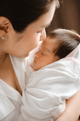 Wall Mural - close-up young woman holding a newborn baby in her arms.
