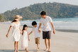 © tirachard - Asian young happy family enjoy vacation on beach in evening. Dad, mom and kid relax walking together near sea when sunset while travel holiday trip. Lifestyle travel holiday vacation summer concept.