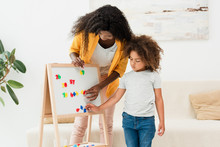 African American mother and daughter touching magnets on whiteboard