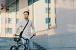 © Prostock-studio - Fast eco city transport. Serious young guy in business clothes, walks with bike at city