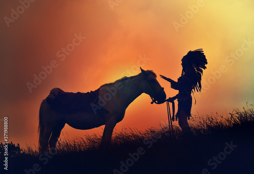 Plakat A young native American Indian woman is silhouetted
with her horse in front of an evening sky. She stands
with her horse in tall grass.