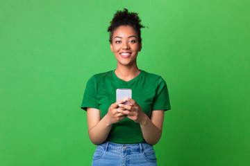 Wall Mural - Smiling afro girl using smart phone at studio