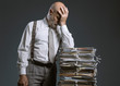 © stokkete - Pensive businessman leaning on a pile of paperwork