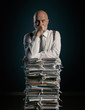 © stokkete - Pensive businessman leaning on a pile of paperwork