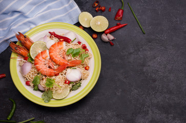 Wall Mural - Fried noodles put in a plate ready to serve With lime shrimp lemongrass shallot coriander spring onion and chili on a black table.