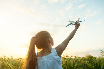 Wall Mural - Little girl holding airplane toy in the green wheat field