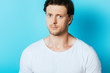 © LIGHTFIELD STUDIOS - Serious man in white t-shirt looking at camera on blue background