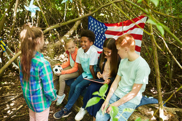 Wall Mural - Multi-ethnic group of kids hiding under branches of big tree while playing in forest or back yard, copy space