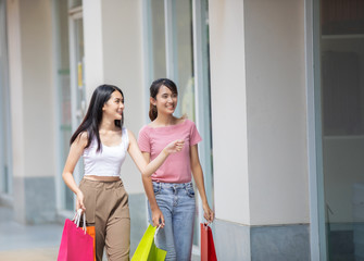 Asian women talking with a friend and holding shopping bag in a shopping mall and they wearing a face mask for protection during coronavirus