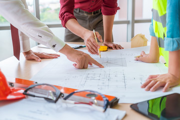 Construction team with business man engineer and architect is brainstorming on working table with building plan