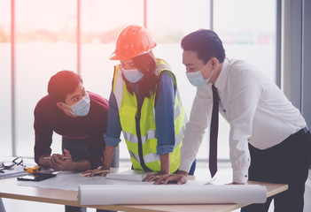 Wall Mural - Construction team with business man engineer and architect is discussing on working table while wearing protective mask for virus protection