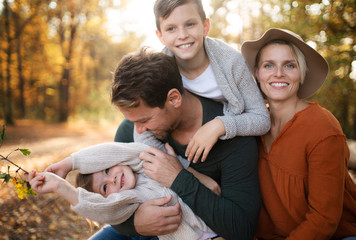 Wall Mural - Beautiful young family with small children on a walk in autumn forest.