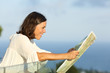 © PheelingsMedia - Adult woman searching location in a map from a balcony