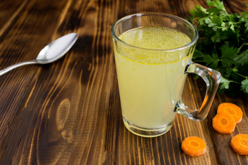 Wall Mural - Chicken broth in the glass on the brown wooden surface