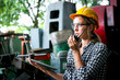 © Stella - Industrial engineer worker wearing helmet and safely glasses holding walkie talkie using a laptop computer at manufacturing plant factory, beautiful young woman working in industry