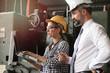 © Stella - Young beautiful woman industrial engineer worker wearing helmet and safety glasses discussing with businessman, using laptop computer, people work at manufacturing industry factory, boss & secretary