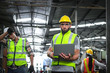 © Stella - Industrial engineer wearing helmet and safe glasses, holding laptop computer for operating machinery at manufacturing plant factory, worker team working together in industry concept