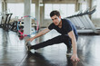 © Nawarit - Athletic men stretching before exercising on yoga mats in the gym. By stretching his leg muscles.