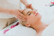 © Nawarit - Beautiful woman lying on the bed for a spa asia massage at luxury spa and relaxation. The masseuse massaged her face and head in the spa room.
