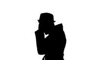 Man In Long Coat Puts On Hat, Black Silhouette On White Background.