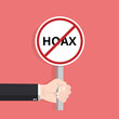 Hand holding hoax word typography sign design illustration. Fight symbol against lies, propaganda and fake news.