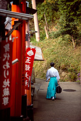 Sticker - Men dress like Shinto priests, wearing white shirts and green pants. Rear view, walking on a walkway in Fushimi Inari Shrine.