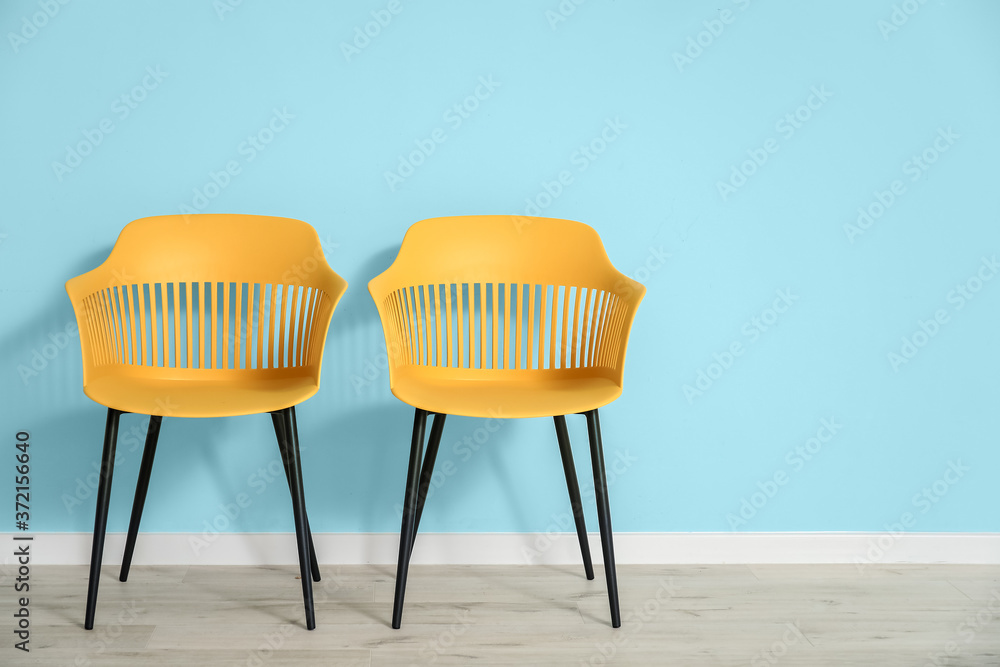 Stylish armchairs near color wall in room