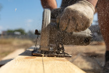 A Worker Cuts A Wooden Board At A Construction Site