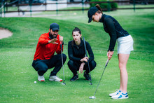 Golf Putting Lesson, Two Young Female Golfers Practicing Putting With Golf Instructor