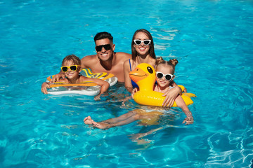 Sticker - Happy family with inflatable rings in outdoor swimming pool on sunny summer day