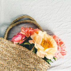 Wall Mural - flat-lay of beautiful peony flowers in straw bag over grey linen table cloth background