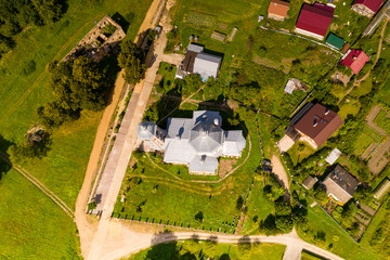 an old manor house turned into ruins of red brick and a church removed from a drone