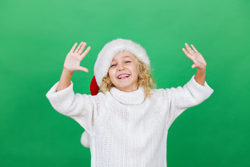 Wall Mural - Merry Christmas Little girl in Santa hat on bright green vivid color background.