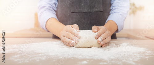 Fotomural Baker chef hand sprinkling flour fresh dough on kitchen table, white background