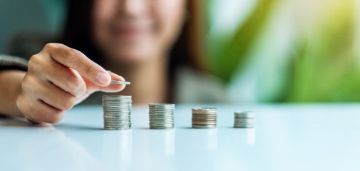 Businesswoman holding and stacking coins on the table