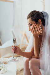 Wall Mural - Selective focus of bride in earring and veil holding mirror near coffee table at home