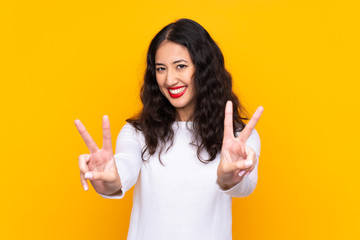 Wall Mural - Mixed race woman over isolated yellow background smiling and showing victory sign