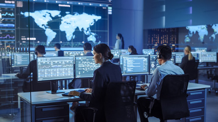Fototapete - Team of Professional Computer Data Science Engineers Work on Desktops with Screens Showing Charts, Graphs, Infographics, Technical Neural Data and Statistics. Low Key Control and Monitoring Room.
