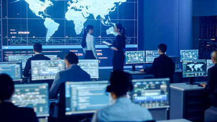 Aufkleber - Project Manager and Computer Science Engineer Talking while Using Big Screen Display Showing Global Map and Data. Telecommunications Company System Control and Monitoring Room.