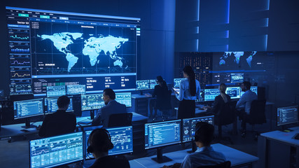 Fototapete - Team of Professional Computer Data Science Engineers Work on Desktops with Screens Showing Charts, Graphs, Infographics, Technical Neural Data and Statistics. Low Key Control and Monitoring Room.